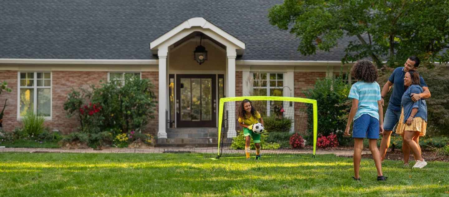 Family playing soccer in the front yard.