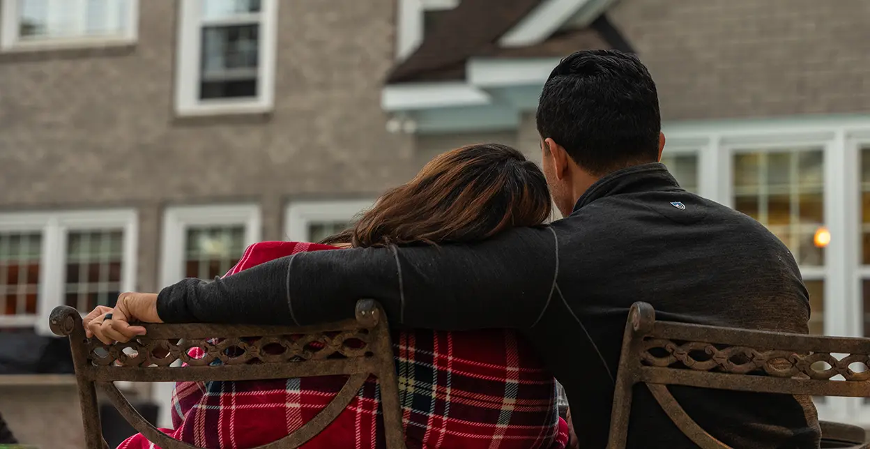 A couple sitting on chairs in their back yard.