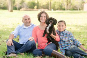 Mosquito Joe owner Kim and her family sitting in the grass and smiling.