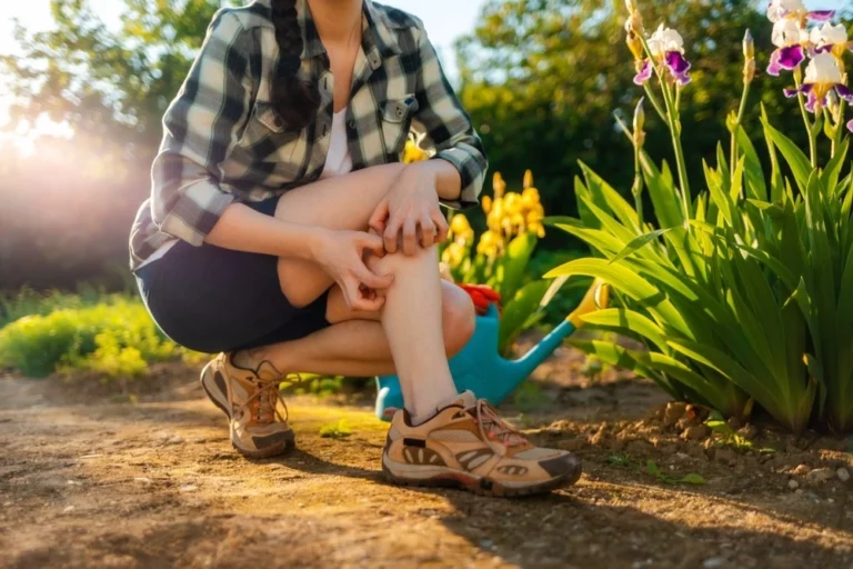 Gardener scratching a mosquito bite while watering flowers outside