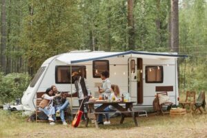 Group of friends enjoying the outdoors under tent and outside of rv 